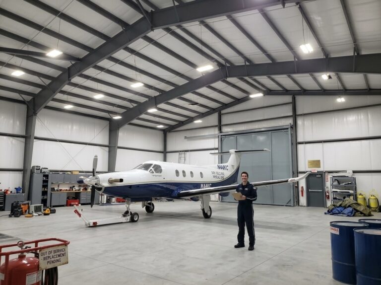 nterior view of a large aircraft hangar featuring steel framing, a stored airplane, maintenance equipment